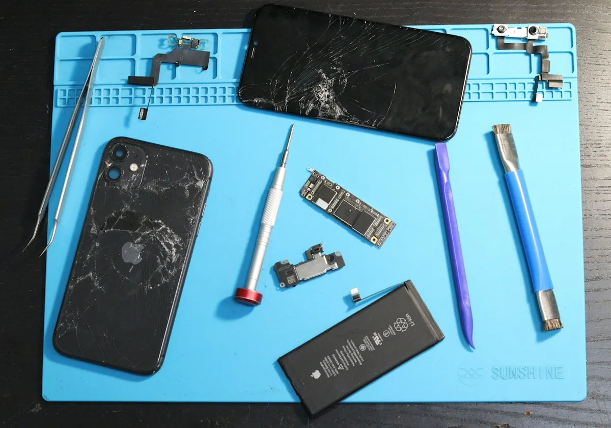 Onarım matı üzerinde sökülmüş akıllı telefon ve tamir aletleri